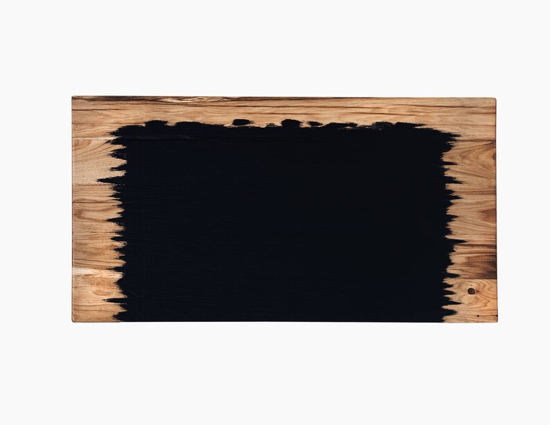 May include: A rectangular wooden board with a black, irregular, painted shape in the center.