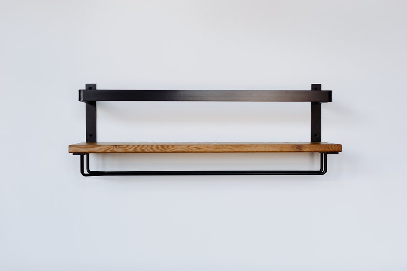 May include: A black metal shelf with a wooden top and a metal rod underneath. The shelf is mounted to a white wall.
