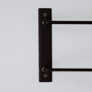 Pode incluir: Toalheiro de parede de metal preto com duas barras. O toalheiro &eacute; fixado &agrave; parede com dois parafusos.