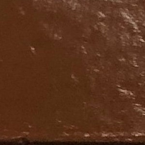 May include: A close-up of a small, square, brown tile with a textured surface.