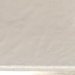 May include: A close-up of a white, smooth surface with a subtle texture. The surface appears to be made of a soft material, possibly fabric or paper.