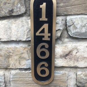May include: A gold-colored metal house number plaque with black background. The number 1466 is displayed in a vertical format.