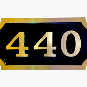 May include: A gold-coloured metal plaque with a black background and the number 440 in gold lettering.