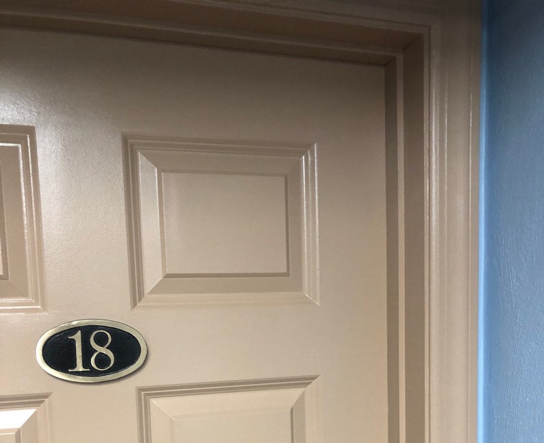 May include: A beige door with a black oval plaque with the number 18 in gold lettering.