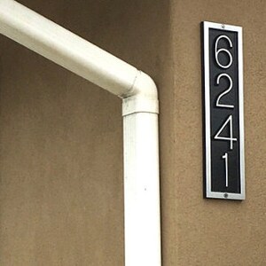 May include: A black and silver house number plaque with the numbers 6241.