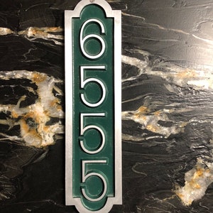 May include: A silver and green house number plaque with the number 6555.