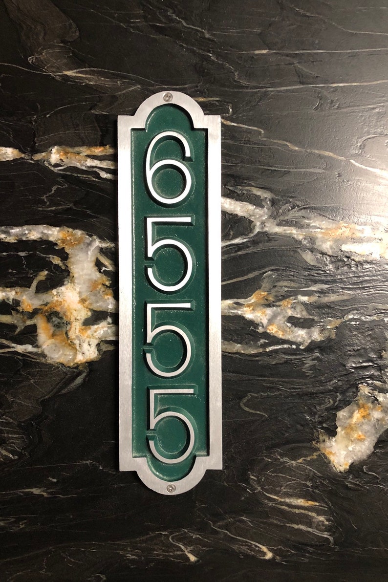 May include: A silver and green house number plaque with the number 6555.