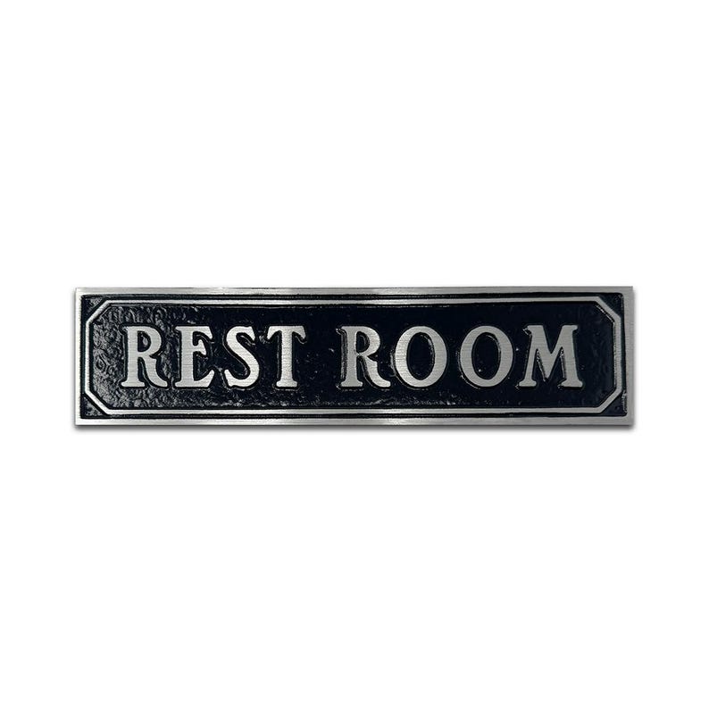 Pu&ograve; includere: Cartello in metallo nero con scritta argentata "REST ROOM".