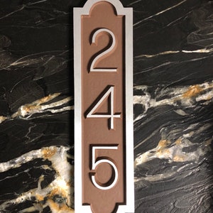 May include: A vertical house number sign with a brown background and silver trim. The numbers 245 are displayed in a vertical line.