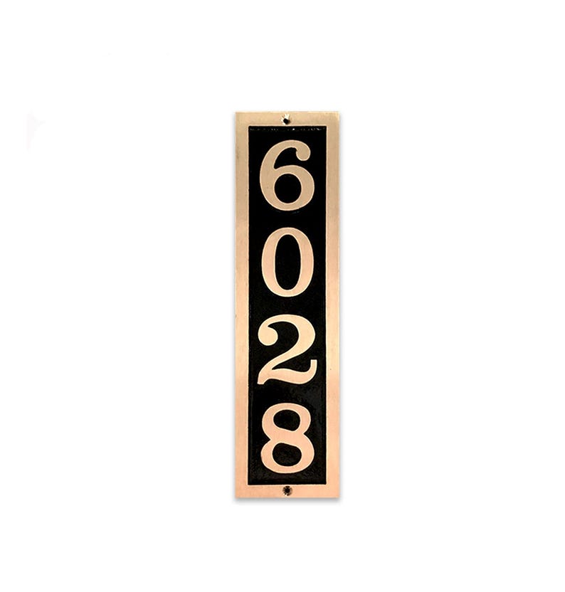 May include: Vertical house number sign with a black background and gold numbers. The numbers are 6028.