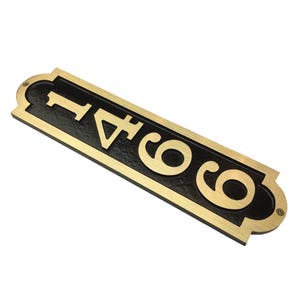 May include: A gold-colored metal house number sign with black background. The number 6041 is displayed in a vertical orientation.