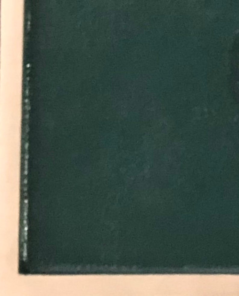May include: A dark green fabric with a subtle texture. The fabric is framed by a light brown border.