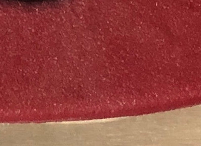May include: Close-up of a deep red, textured surface. The surface has a slightly rough, grainy texture.