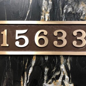 May include: A rectangular bronze plaque with a silver border and the number 15633 in silver lettering.