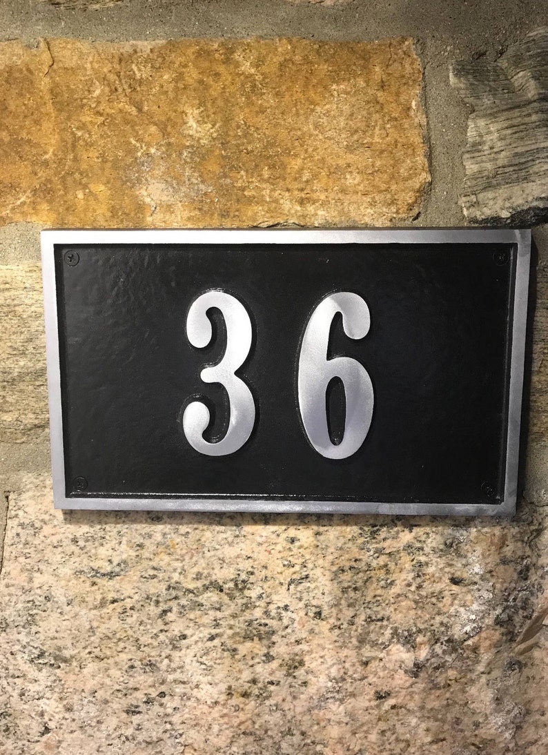 May include: A silver metal house number plaque with a black background. The number 36 is displayed in a silver font.