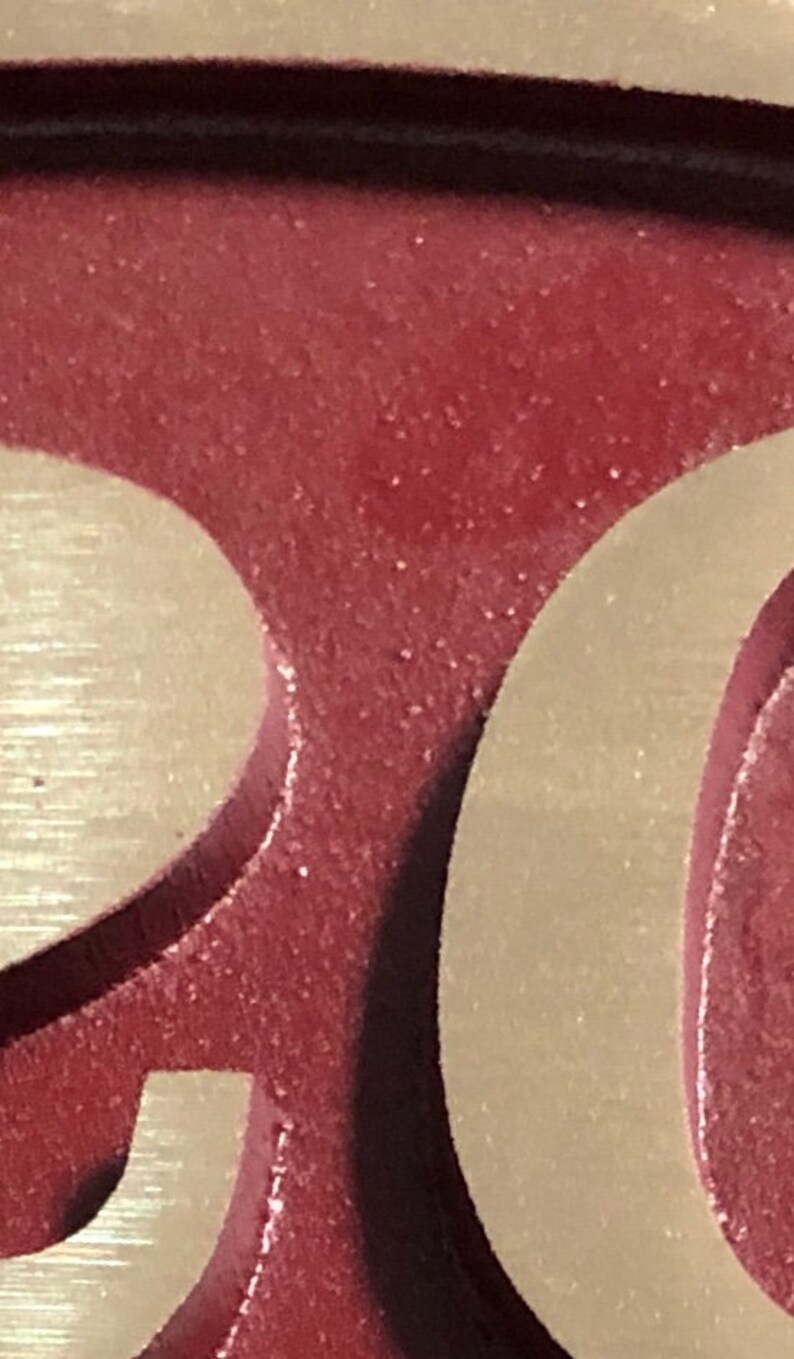 May include: Close-up of a house number plaque with the number "20" in raised, gold lettering on a burgundy background.