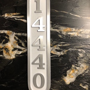 May include: A white metal house number sign with the number 1440 printed in silver on it.