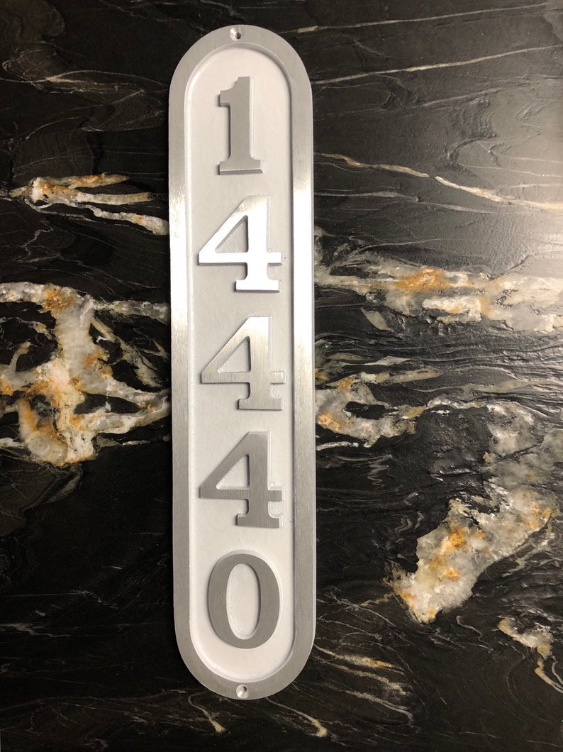 May include: A white metal house number sign with the number 1440 printed in silver on it.