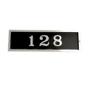 May include: A silver rectangular house number plaque with a black background and the number 128 in white.