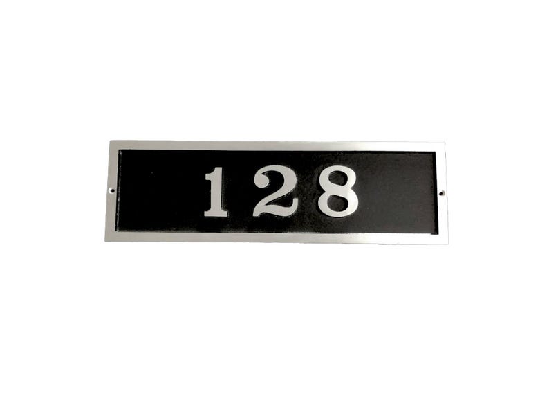 May include: A silver rectangular house number plaque with a black background and the number 128 in white.