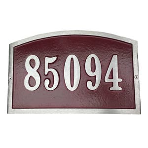 May include: A silver-framed house number plaque with a burgundy background. The number 85094 is displayed in a silver, stylized font.