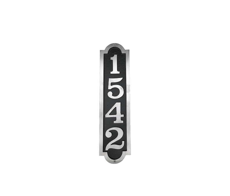 May include: A vertical silver and black house number plaque with the numbers 1542 in white.