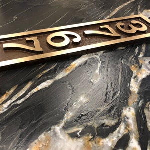 May include: A bronze house number plaque with the number "709" engraved in a raised, stylised font. The plaque is rectangular and has a slightly weathered finish.