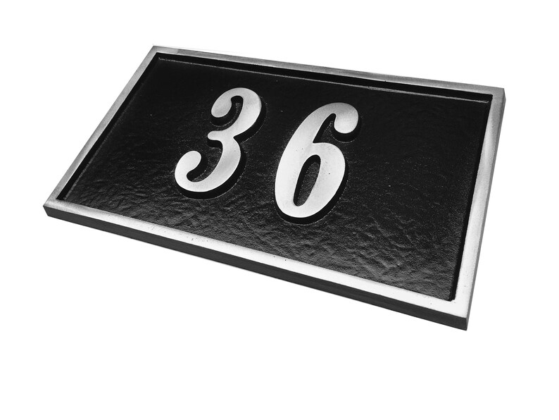 May include: Black house number plaque with a silver border and the number 36 in silver lettering.