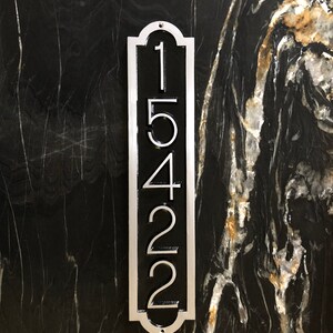 May include: A silver vertical house number plaque with black numbers reading "15422" on a black marble background.