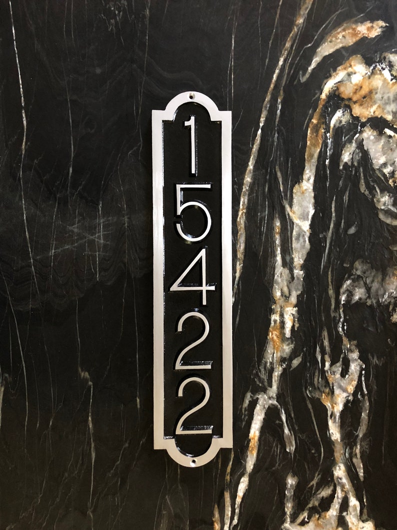 May include: A silver vertical house number plaque with black numbers reading "15422" on a black marble background.