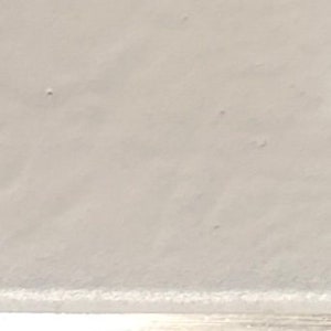 May include: A close-up of a white, smooth surface with a subtle texture. The surface appears to be made of a soft material, possibly fabric or paper.