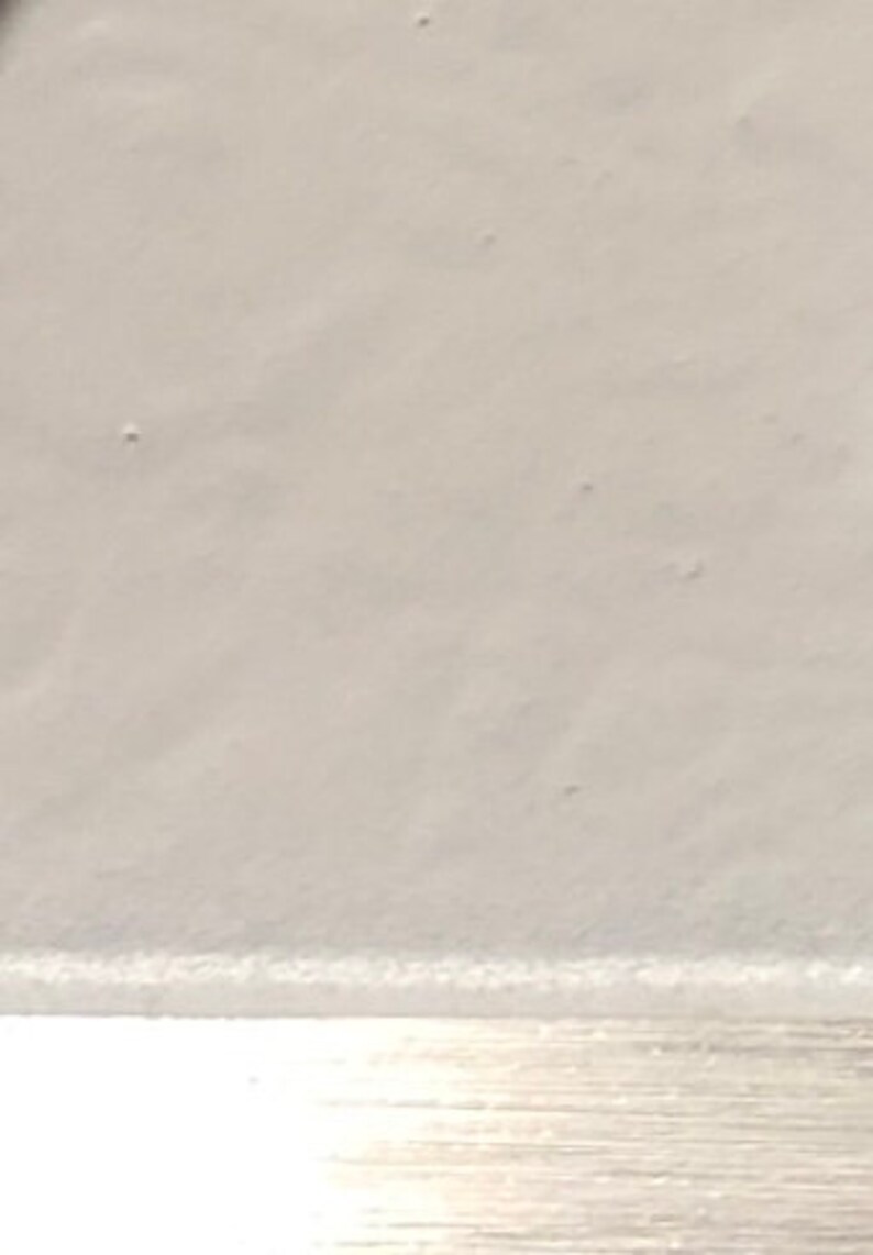 May include: A close-up of a white, smooth surface with a subtle texture. The surface appears to be made of a soft material, possibly fabric or paper.