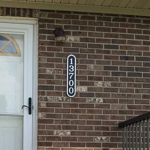 May include: Black and white house number sign with the number 13700 on a brick wall.