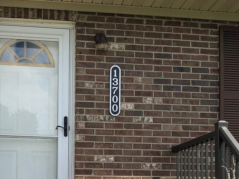 May include: Black and white house number sign with the number 13700 on a brick wall.