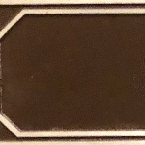 May include: A brown rectangular sign with a white border. The sign has a beveled edge and a slightly textured surface.
