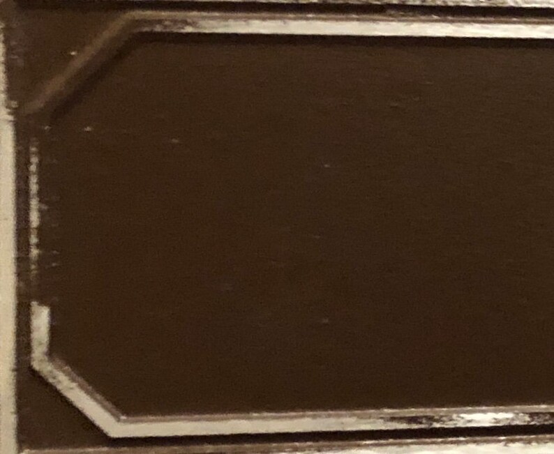 May include: A brown wooden plaque with a silver border. The plaque has a smooth surface and a slightly raised edge.