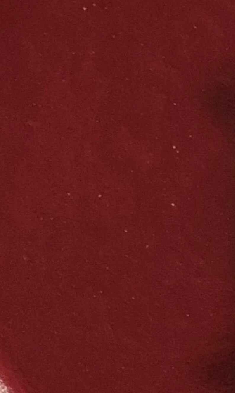 May include: A close-up of a deep red, smooth, solid surface.