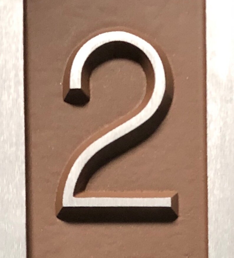 May include: A close-up of a silver number "2" embossed on a brown background.