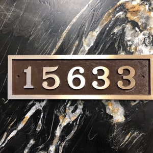 May include: A silver plaque with a brown background and the number 15633 in silver lettering.