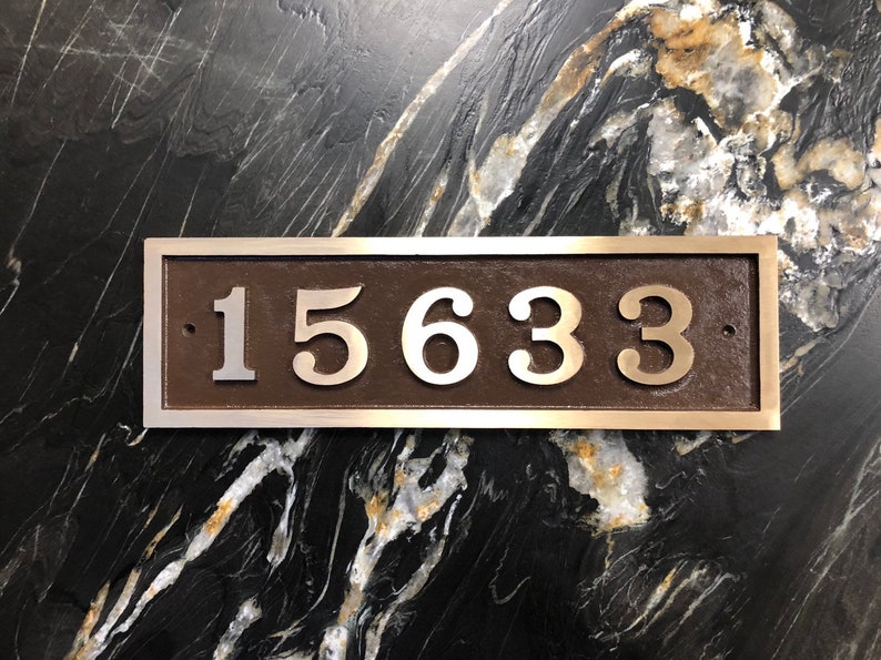 May include: A silver plaque with a brown background and the number 15633 in silver lettering.
