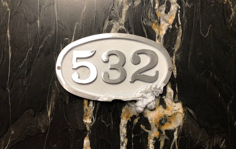 May include: White oval-shaped house number sign with silver numbers "532" on a black background.