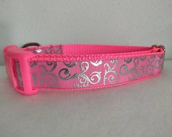 May include: A pink dog collar with a silver floral pattern.