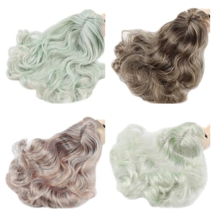 Op de afbeelding: Vier poppenpruiken in verschillende kleuren. De pruiken zijn lang en golvend. De kleuren zijn lichtgroen, bruin, lichtgrijs met roze highlights en lichtgroen met witte highlights.