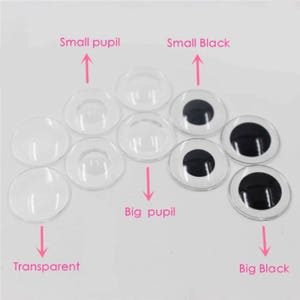 May include: A selection of clear and black plastic craft eyes with different pupil sizes. The image shows transparent eyes, eyes with small pupils, and eyes with large black pupils. Text labels read "Small pupil", "Big pupil", "Small Black", "Big Black", and "Transparent".