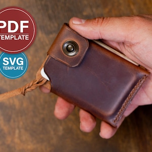 May include: A brown leather wallet featuring a snap button closure and a braided leather pull tab. The wallet includes digital file labels reading PDF TEMPLATE and SVG TEMPLATE. The design shows visible stitching along the edges and a smooth finish.