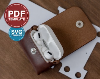 May include: A brown leather case with a white plastic insert for holding wireless earbuds. The case has a snap closure and a metal button. The case is open and the earbuds are visible inside.