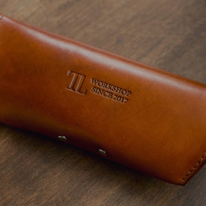 May include: A brown leather glasses case with the text "TL Workshop Since 2017" embossed on the front.