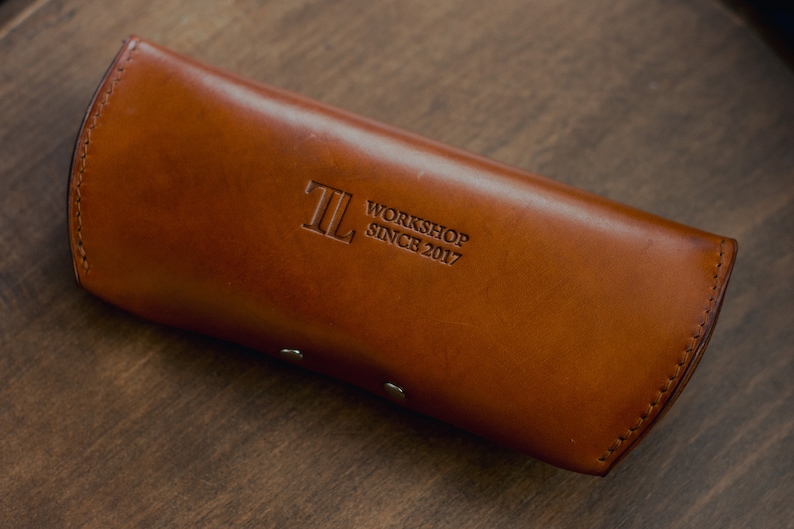 May include: A brown leather glasses case with the text "TL Workshop Since 2017" embossed on the front.