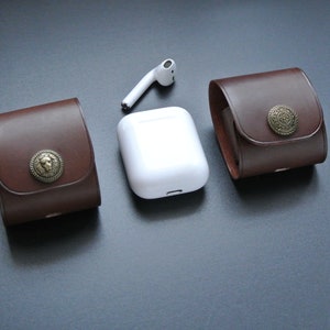 May include: Two brown leather cases with metal accents and a white wireless charging case for earbuds.