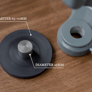 Puede incluir: Primer plano de una base de metal negro con un poste de metal plateado. La base tiene un di&aacute;metro de 65-70 mm y el poste tiene un di&aacute;metro de 19 mm.